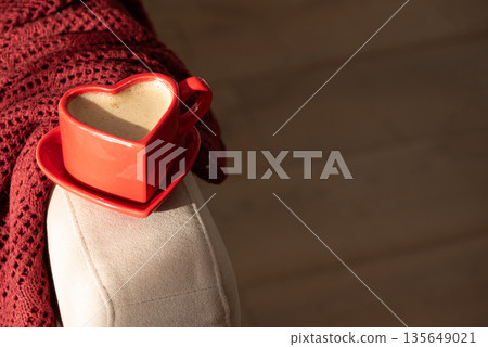 Heart Shaped Coffee Cup on Armchair with Red Blanket. Cozy Valentines Day Still Life Heart Shaped Coffee Cup on Armchair with Red Blanket. Cozy Valentines Day Still Life 135649021