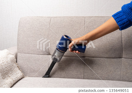 A person is cleaning a couch with a vacuum cleaner A person is cleaning a couch with a vacuum cleaner 135649051