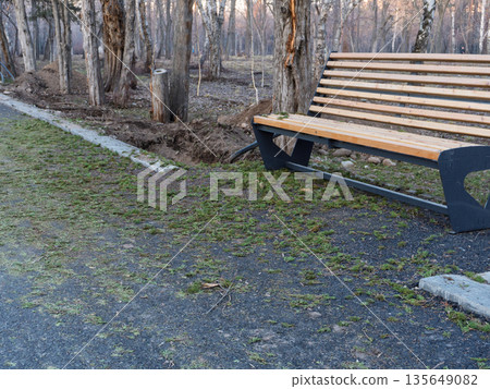 Empty wooden bench in an urban park near a new pedestrian curb, spring or autumn. Empty wooden bench in an urban park near a new pedestrian curb, spring or autumn. 135649082