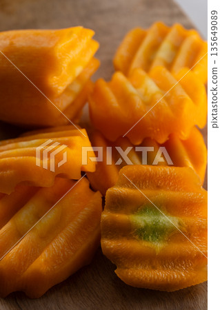 Fresh crinkle-cut carrot slices stacked on a rustic wooden surface. Raw orange vegetable ingredient with wavy texture Fresh crinkle-cut carrot slices stacked on a rustic wooden surface. Raw orange vegetable ingredient with wavy texture 135649089