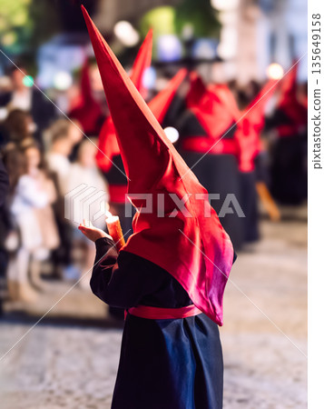 Child Nazareno during Holy Week procession holding a candle Child Nazareno during Holy Week procession holding a candle 135649158