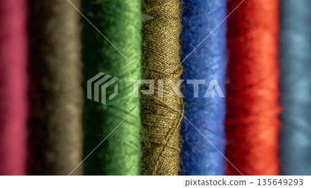Close-up of vibrant textile threads in a row with selective focus and soft bokeh 135649293