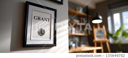 Close-up of a framed wall art with the word 'GRANT' and a decorative watch in a modern cozy room with shelves and natural light 135649782