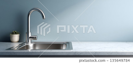 Modern kitchen sink with stainless steel faucet and marble countertop against a light blue wall with small potted plant 135649784