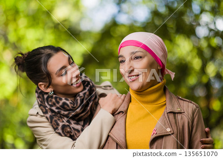 Cancer survivor mother and daughter smiling in park 135651070