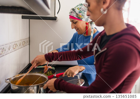 Mother with cancer and daughter cooking healthy meal 135651085