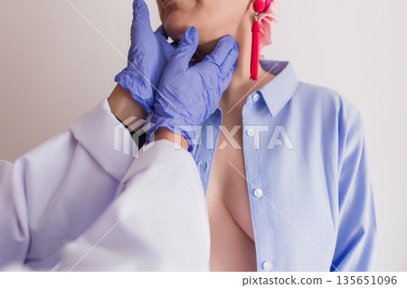 Doctor examining female patient's neck, checking thyroid gland 135651096