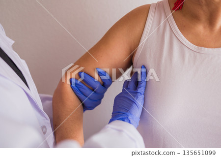 Doctor performing breast cancer screening examination 135651099