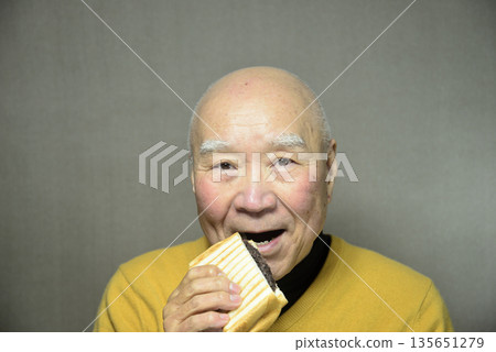 An old man eating a hot sandwich with bean paste An old man eating a hot sandwich with bean paste 135651279