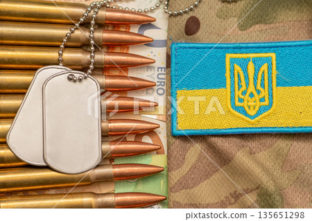 Soldier identification tags and ammunition on euro banknotes with Ukraine patch. 135651298