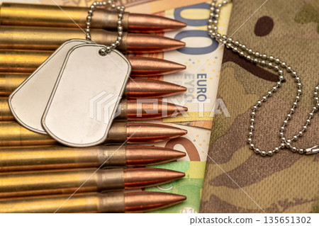 Soldier identification tags and ammunition placed near camouflage fabric. 135651302