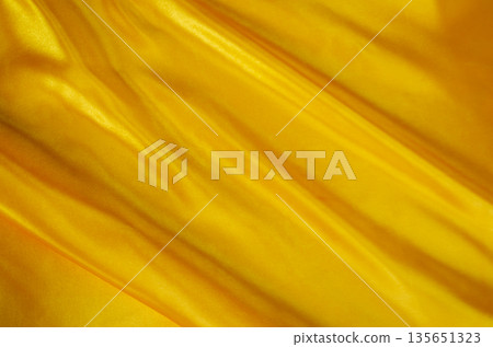 Rich golden silk texture with dynamic folds and luminous sheen for premium abstract design projects. 135651323