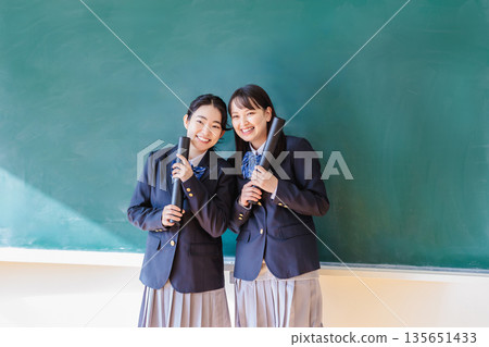 Female student holding a diploma in front of a blackboard 135651433