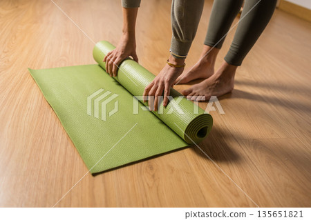 Woman unrolling yoga mat preparing for vinyasa class Woman unrolling yoga mat preparing for vinyasa class 135651821