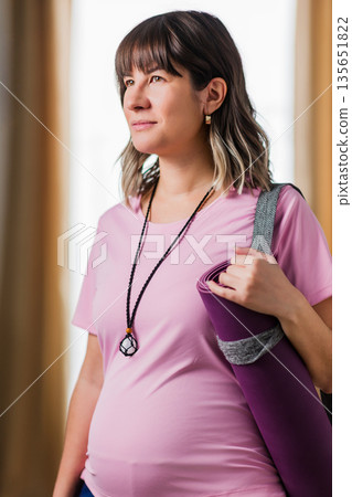 Hispanic pregnant woman looking away carrying yoga mat 135651822