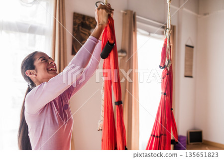 Young latin woman enjoying aerial yoga practice Young latin woman enjoying aerial yoga practice 135651823