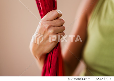 Woman's hand gripping red aerial yoga hammock 135651827