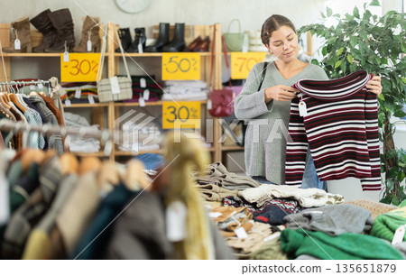 Pregnant woman choosing a sweater in a clothing store Pregnant woman choosing a sweater in a clothing store 135651879