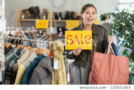 Female model with poster in hands announces mega sale 135651903