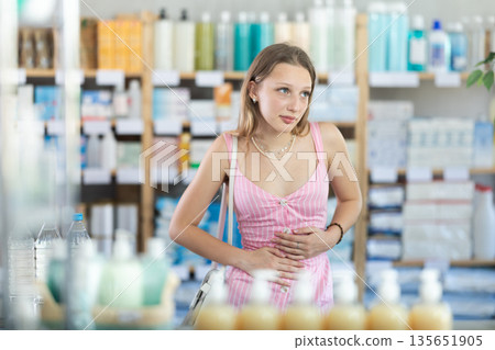 Woman experiences stomach pain while buying in supermarket 135651905