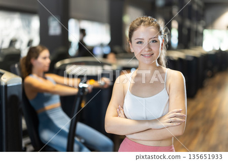 Positive young girl standing in well-equipped gym Positive young girl standing in well-equipped gym 135651933