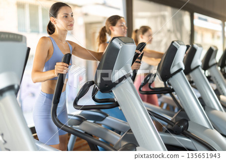 Woman training on elliptical machine 135651943
