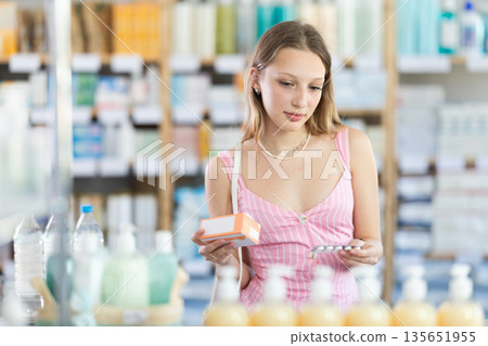 Woman in summer dress choosing pills in pharmacy Woman in summer dress choosing pills in pharmacy 135651955
