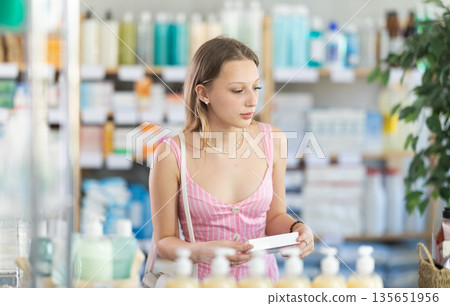 Woman in summer dress choosing pills in pharmacy Woman in summer dress choosing pills in pharmacy 135651956