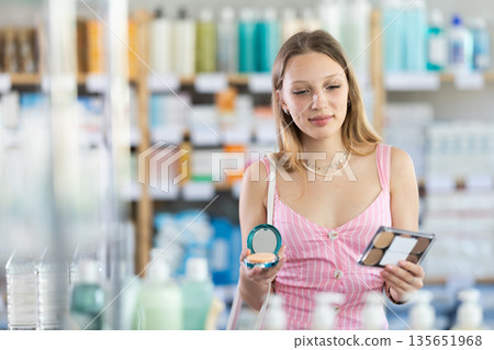 Woman in a dress choosing cosmetics in pharmacy Woman in a dress choosing cosmetics in pharmacy 135651968