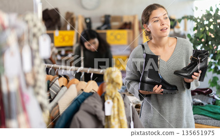 European woman chooses boots with heels and black shoes in the store European woman chooses boots with heels and black shoes in the store 135651975