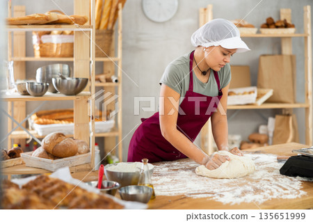 Woman works in bakery as baker, kneads dough, works with flour. Woman works in bakery as baker, kneads dough, works with flour. 135651999
