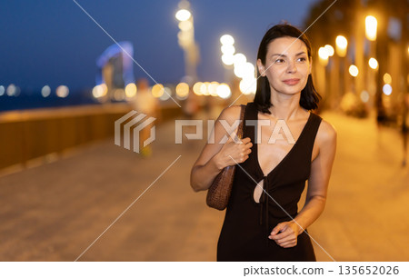 At night, slender female brunette walks in vicinity of beach in Barceloneta At night, slender female brunette walks in vicinity of beach in Barceloneta 135652026