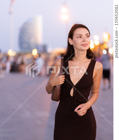 In evening, girl walks around old city district Barceloneta, pedestrian embankment 135652082
