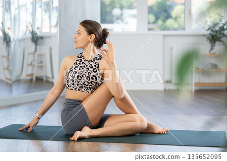 Young woman practicing yoga in ardha matsyendrasana pose Young woman practicing yoga in ardha matsyendrasana pose 135652095