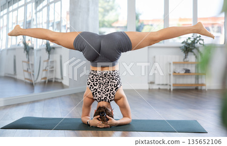 Lover of active lifestyle on yoga mat perform doing shirshasana in gym 135652106
