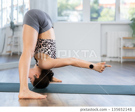 Sporty young girl performing dynamic asanas in yoga studio Sporty young girl performing dynamic asanas in yoga studio 135652148