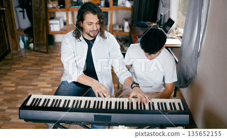 Teacher mentoring student playing digital piano Teacher mentoring student playing digital piano 135652155