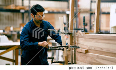 Woodworker clamping timber pieces in workshop Woodworker clamping timber pieces in workshop 135652371