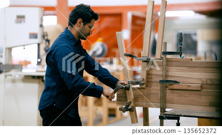 Woodworker assembling timber furniture in workshop Woodworker assembling timber furniture in workshop 135652372