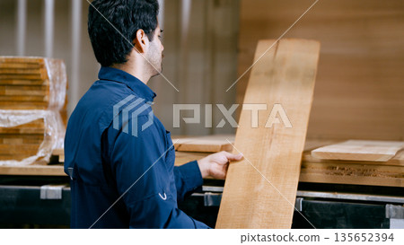 Woodworker selecting natural plank at carpentry workshop 135652394