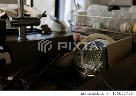 A dimly lit kitchen where housework has been neglected and piles of dishes. A dimly lit kitchen where housework has been neglected and piles of dishes. 135652736
