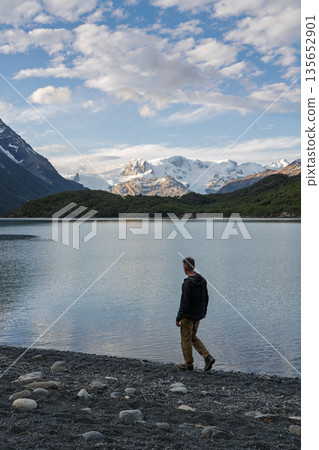 Hiker walking shore of Lago Dickson viewing snowy mountains, Patagonia, Chile 135652901