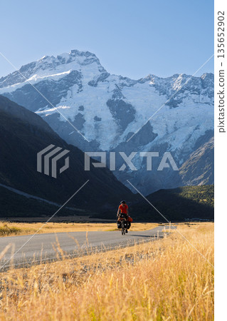 Cyclist touring past massive Mount Sefton glacier near Mount Cook, New Zealand Cyclist touring past massive Mount Sefton glacier near Mount Cook, New Zealand 135652902