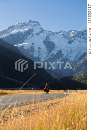Cyclist riding past massive glaciers near Mount Cook Village, New Zealand Cyclist riding past massive glaciers near Mount Cook Village, New Zealand 135652917