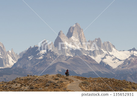 Cyclist bikepacking in front of massive Mount Fitz Roy, Patagonia, Argentina 135652931