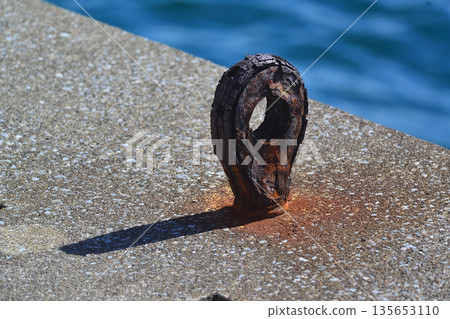 An old, rusty, nostalgic anchor used to tie a ship's rope to the pier An old, rusty, nostalgic anchor used to tie a ship's rope to the pier 135653110