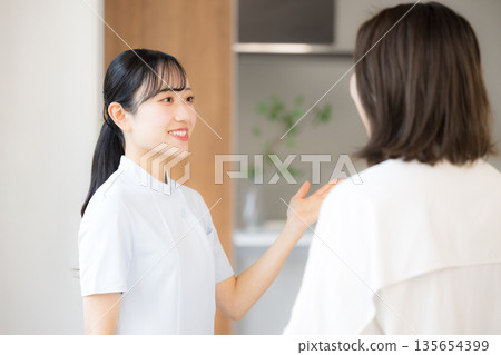 這是診所接待處的場景，護士或其他醫務人員正在仔細地向病人解釋和指導。 135654399