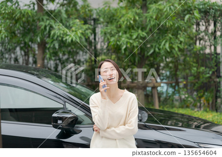 一名女子站在車前打電話 135654604