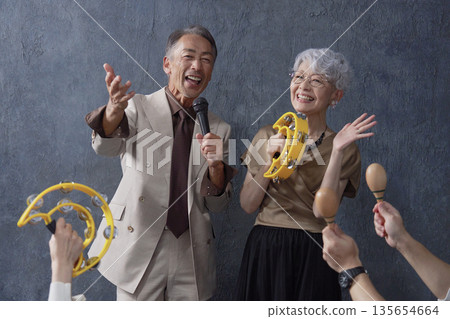 Senior men and women singing karaoke on a black background Senior men and women singing karaoke on a black background 135654664
