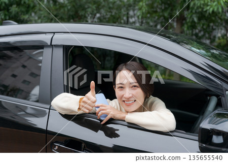 Woman peeking out of car door Woman peeking out of car door 135655540